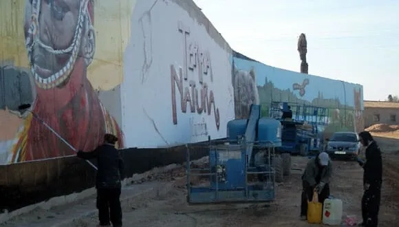 Grafiteros pintando mural Terra Natura Murcia con retrato africano y logo del parque