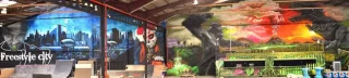 Murales artísticos en skatepark cubierto con escenas urbanas y figuras de fantasía.