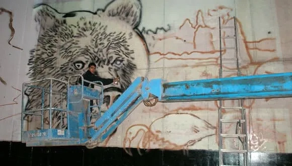 Grafitero pintando mural de oso en Terra Natura Murcia arte urbano fauna salvaje Espinardo
