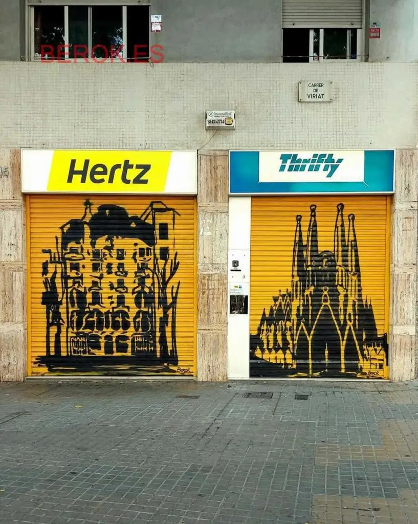 Graffiti en persianas de Hertz y Thrifty con murales urbanos en negro sobre fondo amarillo que representan la Pedrera y la Sagrada Familia de Gaudí.