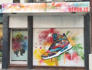 Graffiti de zapatilla deportiva colorida en la persiana de la tienda Tapapeus en Manresa