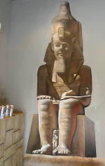 Mural hiperrealista de estatua egipcia sentado en pared interior.