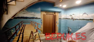 Pintura mural realista de un embarcadero con paisaje lacustre en el interior de un hotel en Mollerussa, Lleida, decorado con graffiti profesional.