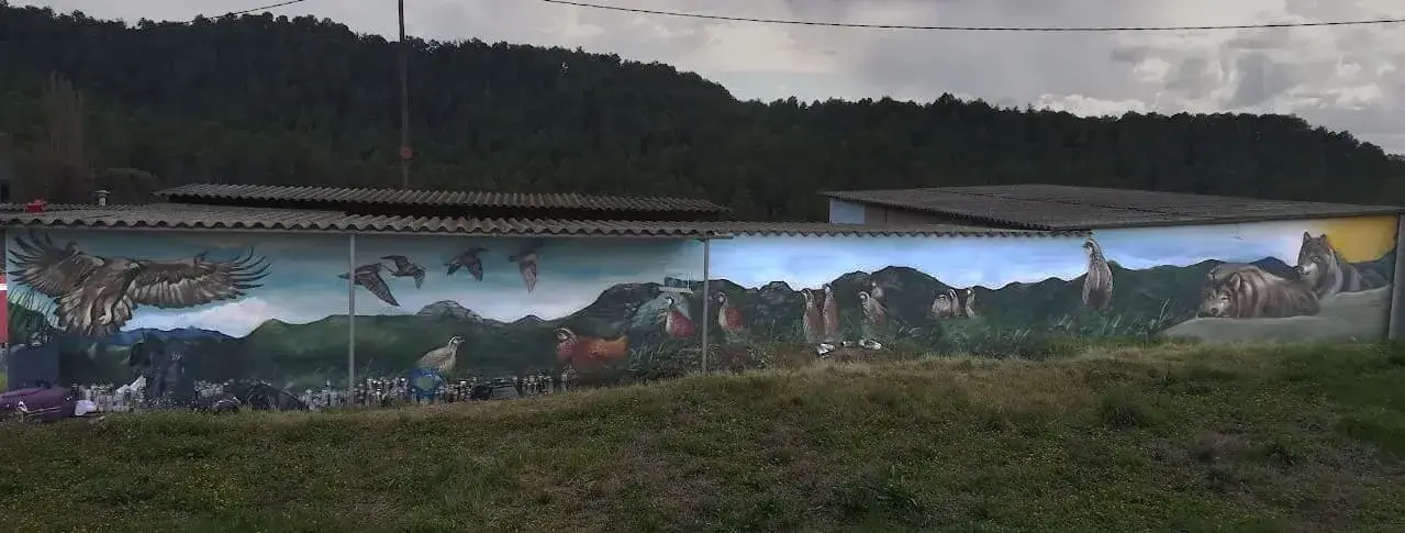Graffiti mural en Berguedà con águila, buitres, lobos, caballos, cabras, perdices y aves en vuelo sobre paisaje de montaña.