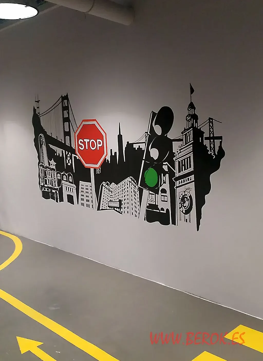 mural artístico en interior de oficinas con skyline urbano, señales de tráfico y stop