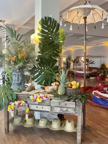 Decoración tropical con hojas de costilla de Adán y frutas en evento corporativo temático