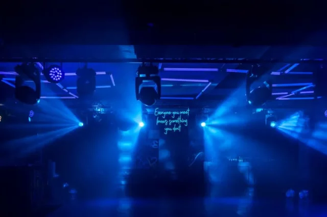 Escenario iluminado con luces azules en evento temático años 80s y 90s