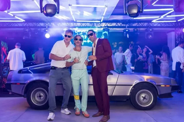 Invitados junto a coche DeLorean en evento temático Regreso al Futuro