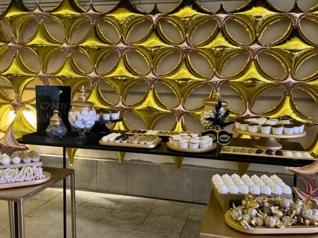 Mesa de dulces con decoración dorada en evento corporativo premium