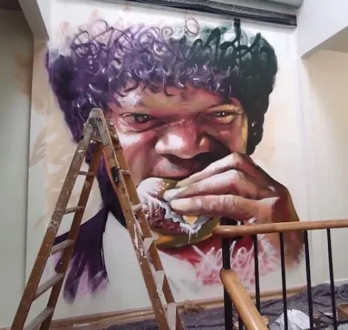 Graffiti hiperrealista mural de Pulp Fiction con hamburguesa Graffiti hiperrealista Pulp Fiction personaje comiendo hamburguesa