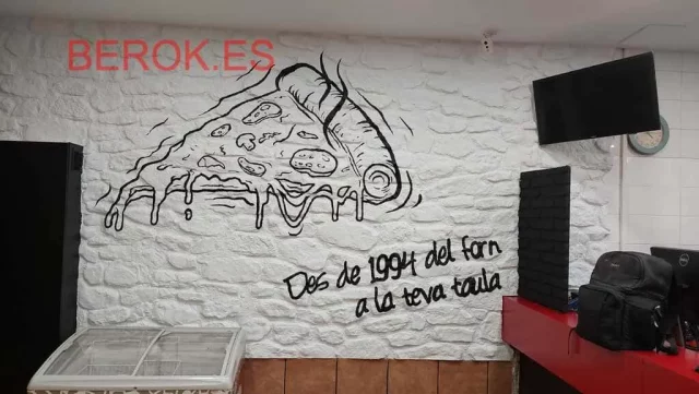 Mural blanco y negro con porción de pizza y frase escrita en catalán