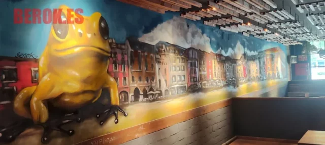 Mural con rana amarilla gigante y casas de Vic