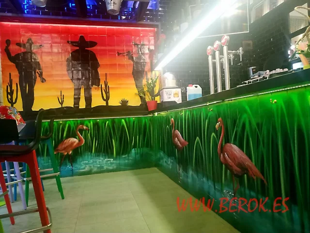 Mural con flamencos rosados y siluetas mexicanas en restaurante colorido