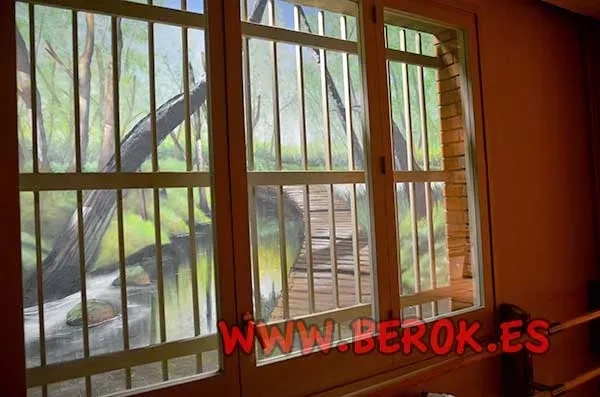 Mural de bosque con puente y vegetación creando profundidad en patio interior.