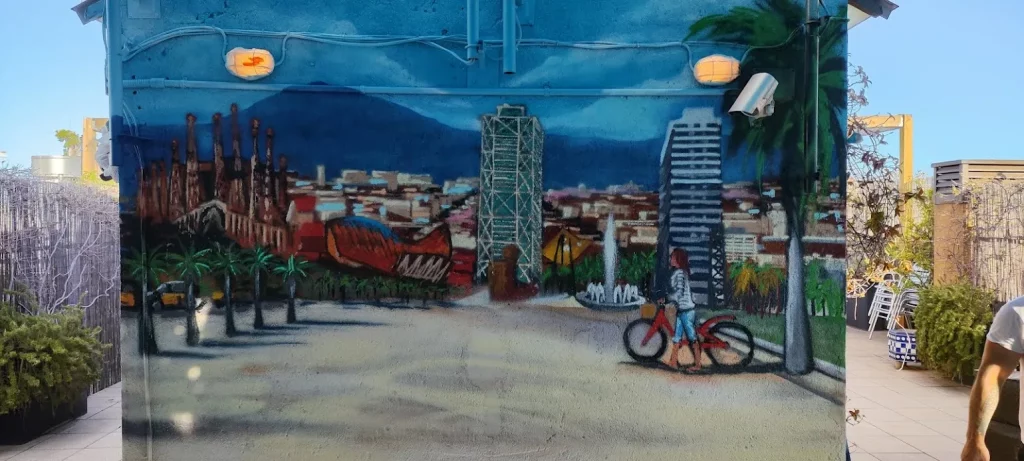 Mural del skyline de Barcelona con ciclista y edificios emblemáticos