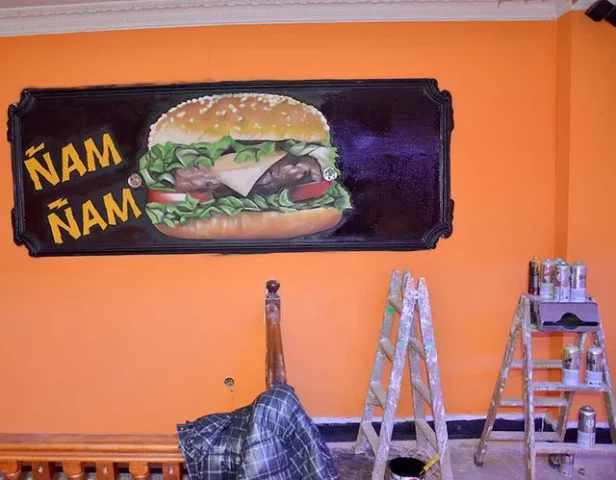 Mural hamburguesa gigante con texto Ñam Ñam en pared naranja