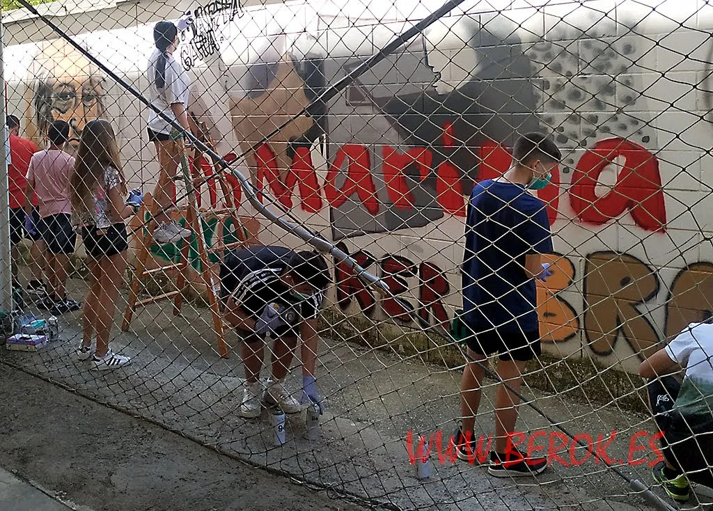 Taller de graffiti en Sitges para jóvenes artistas decorando muro escolar