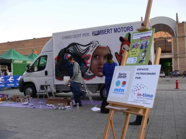 Exhibición de graffiti en camión durante evento urbano Camión pintado durante exhibición de graffiti con retrato femenino