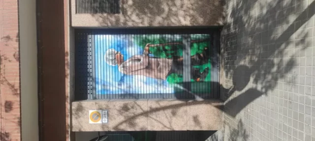 Graffiti persiana residencia de ancianos con retrato de abuela Graffiti en persiana de residencia de ancianos con mujer mayor caminando