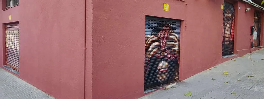 Graffiti de mono sabio tapándose los ojos con un bistec en persiana de bar en Martorelles
