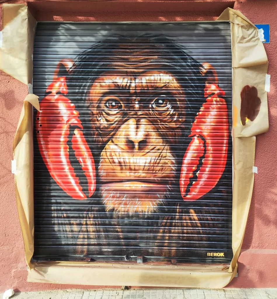 Graffiti de mono sabio con langostas tapando los oídos en persiana en Martorelles