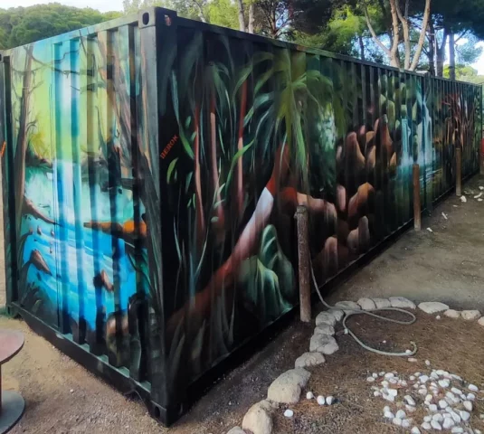 Decoración mural de selva y vegetación pintada en contenedores marítimos en Barcelona