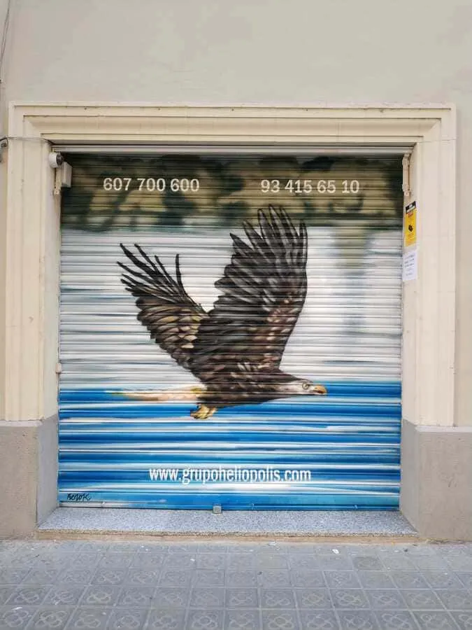 Graffiti de águila en vuelo pintado en persiana de negocio con fondo de cielo y mar