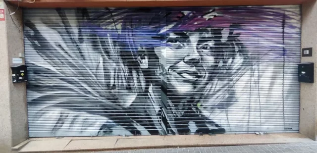 Graffiti de retrato femenino realista en persiana metálica en Barcelona
