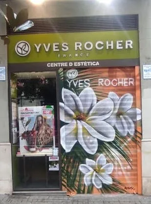 Graffiti floral realista pintado en persiana Yves Rocher con flores blancas y hojas verdes