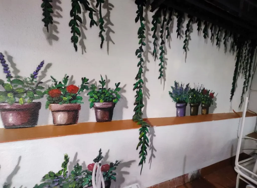 Pintura mural trampantojo de plantas y macetas en patio interior decorado en Barcelona