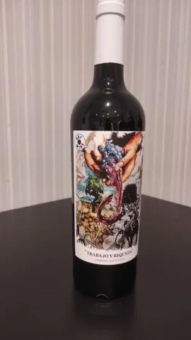 Etiqueta de vino con ilustración artística de manos exprimiendo uvas y paisaje agrícola