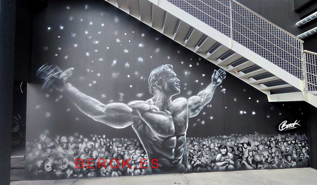 Graffiti culturista Arnold Schwarzenegger gimnasio mural blanco y negro con efecto luces escenario y público difuminado
