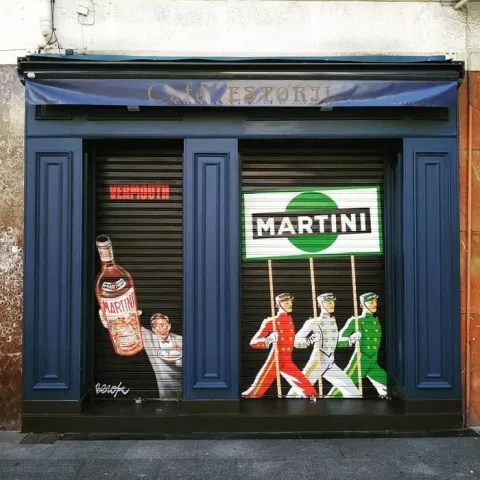 Graffiti en persiana metálica de bar en Bilbao con ilustración vintage de Martini, arte urbano profesional País Vasco.