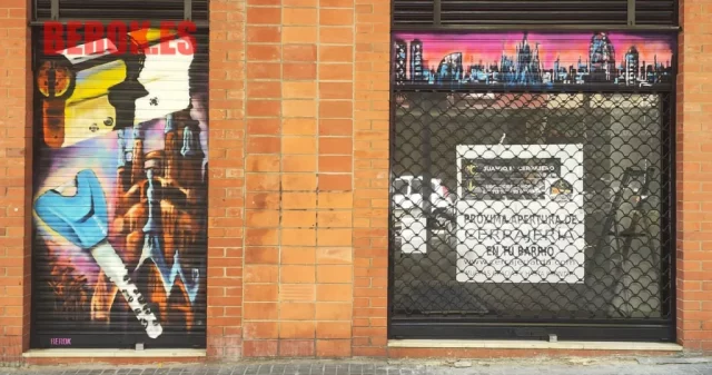 Graffiti herramientas cerrajería y skyline urbano en persiana comercial