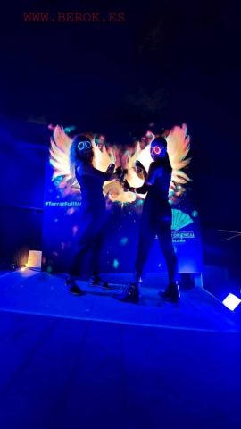 Photocall fluorescente con alas luminosas y performers bajo luz UV en evento del Hotel Mandarin Oriental.