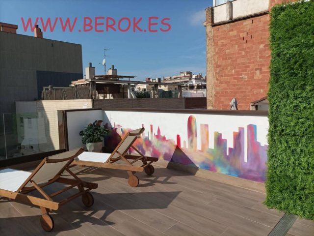 Terraza de hotel con mural minimalista del skyline de Barcelona y jardín vertical decorativo.