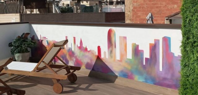 Skyline de Barcelona en terraza moderna de hotel Terraza de hotel con mural minimalista del skyline de Barcelona y jardín vertical decorativo.