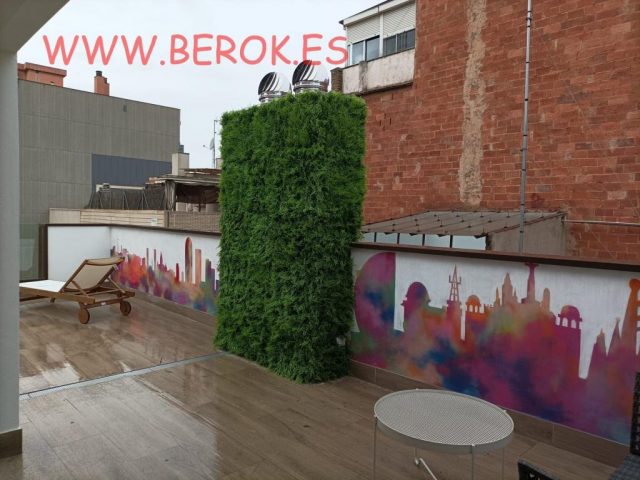 Terraza de hotel con mural del skyline de Barcelona en colores acuarela y jardín vertical.
