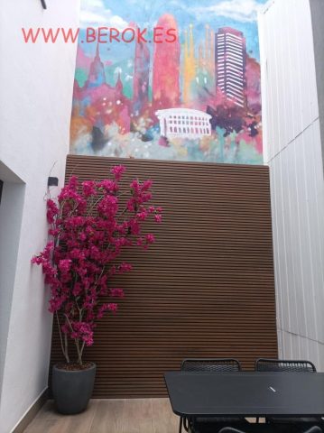 Mural colorido del skyline de Barcelona en patio interior de hotel moderno.
