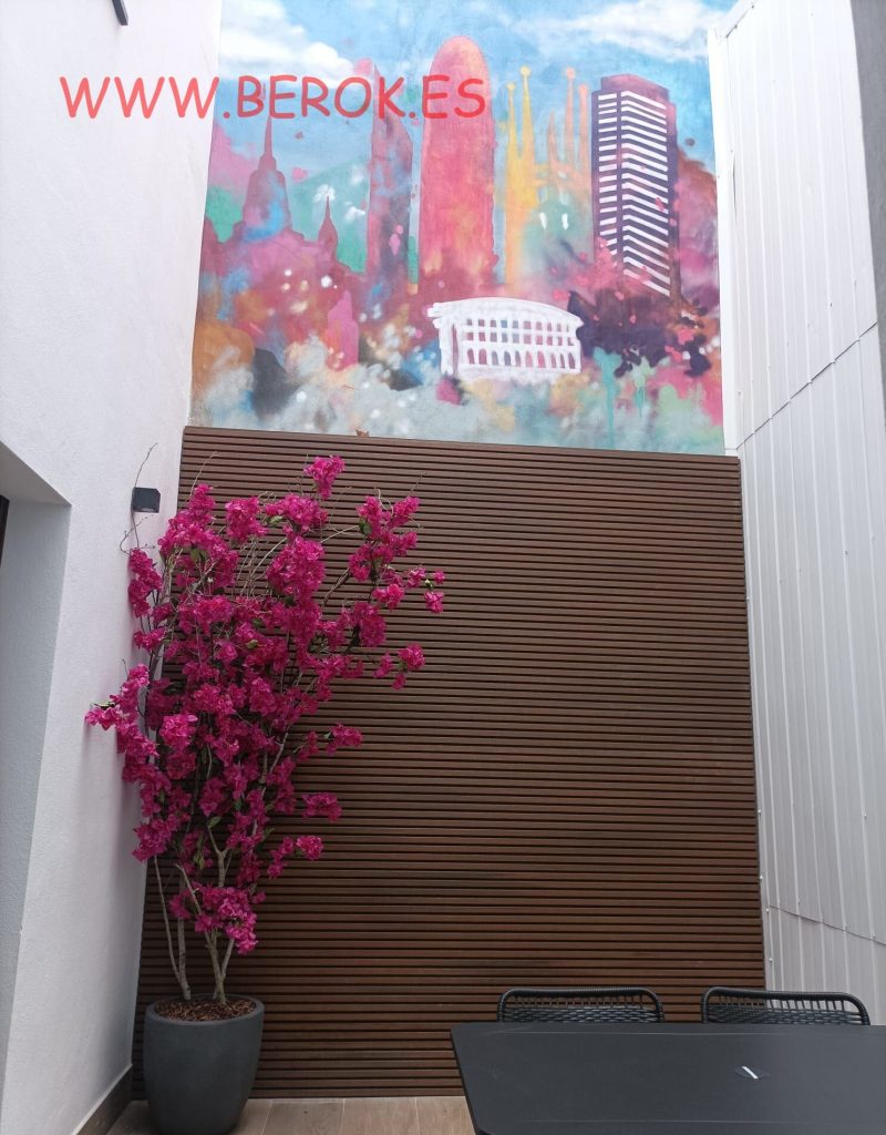 Mural colorido del skyline de Barcelona en patio interior de hotel moderno.
