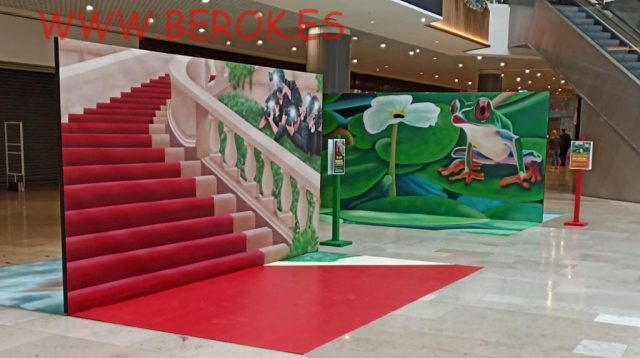 Trampantojos 3D de escalera roja y rana tropical instalados en un centro comercial.