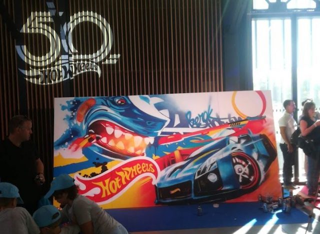 Graffiti Hot Wheels 50 aniversario París con coche deportivo y tiburón en evento
