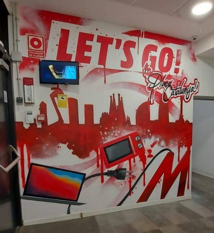 Mural corporativo en oficinas de MediaMarkt Plaza Catalunya con skyline de Barcelona y diseño tecnológico.