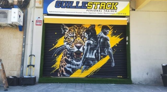 Graffiti fitness Guillestack con jaguar Graffiti mural para gimnasio privado Guillestack con jaguar realista y atletas sobre persiana metálica.