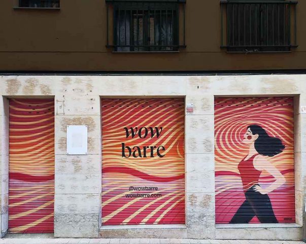 Graffiti en persianas de estudio barre con mural femenino, logo Wow Barre y fondo dinámico en tonos rojos y naranjas