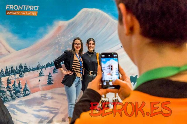 Photocall mural de montaña nevada para evento Frontpro con personas posando delante del paisaje pintado.