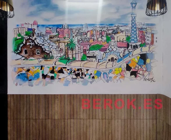 Mural pintado a mano del Parque Güell con dragón de Gaudí, trencadís, palmeras, casas modernistas y skyline de Barcelona en restaurante