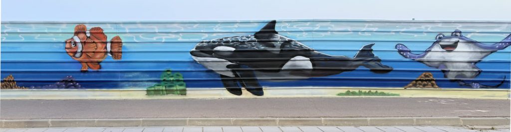 Graffiti de orca y raya marina en mural de arte urbano costero