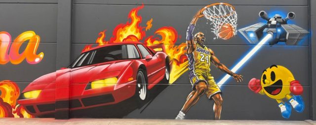 Graffiti con Kobe Bryant haciendo un mate junto a un coche deportivo rojo y Pac-Man.