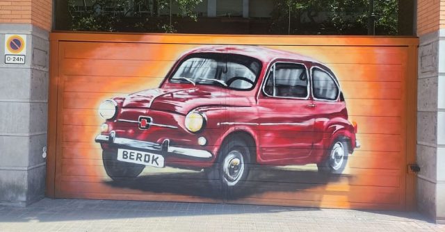 Graffiti de un Seat 600 rojo pintado sobre una puerta de garaje.